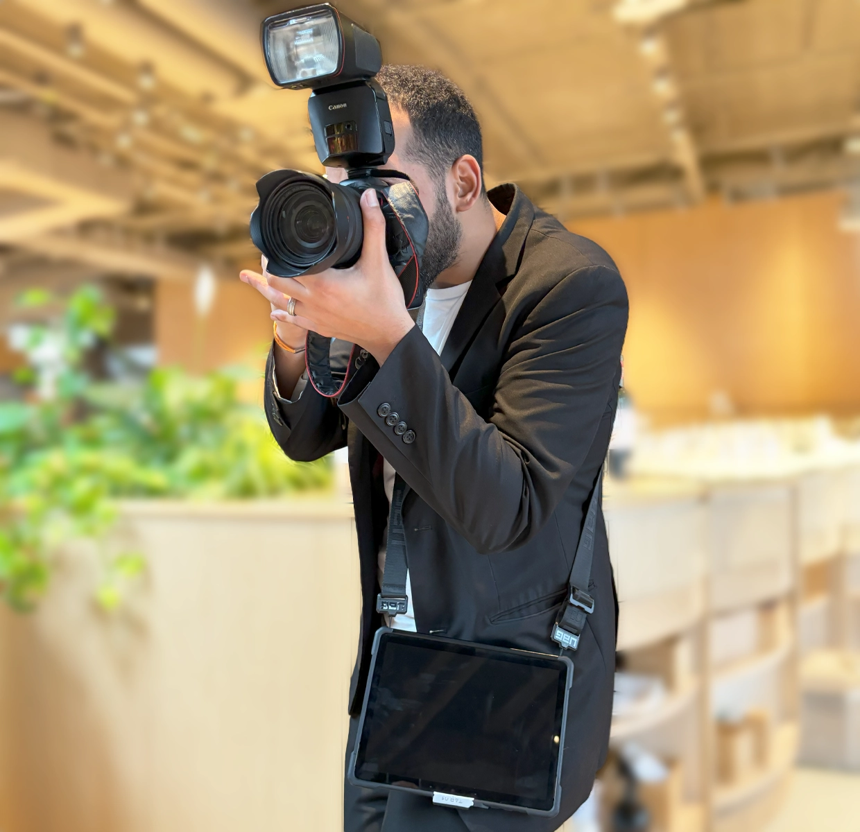 A focused photographer captures moments at a social event, equipped with a professional DSLR camera and portable printing station.