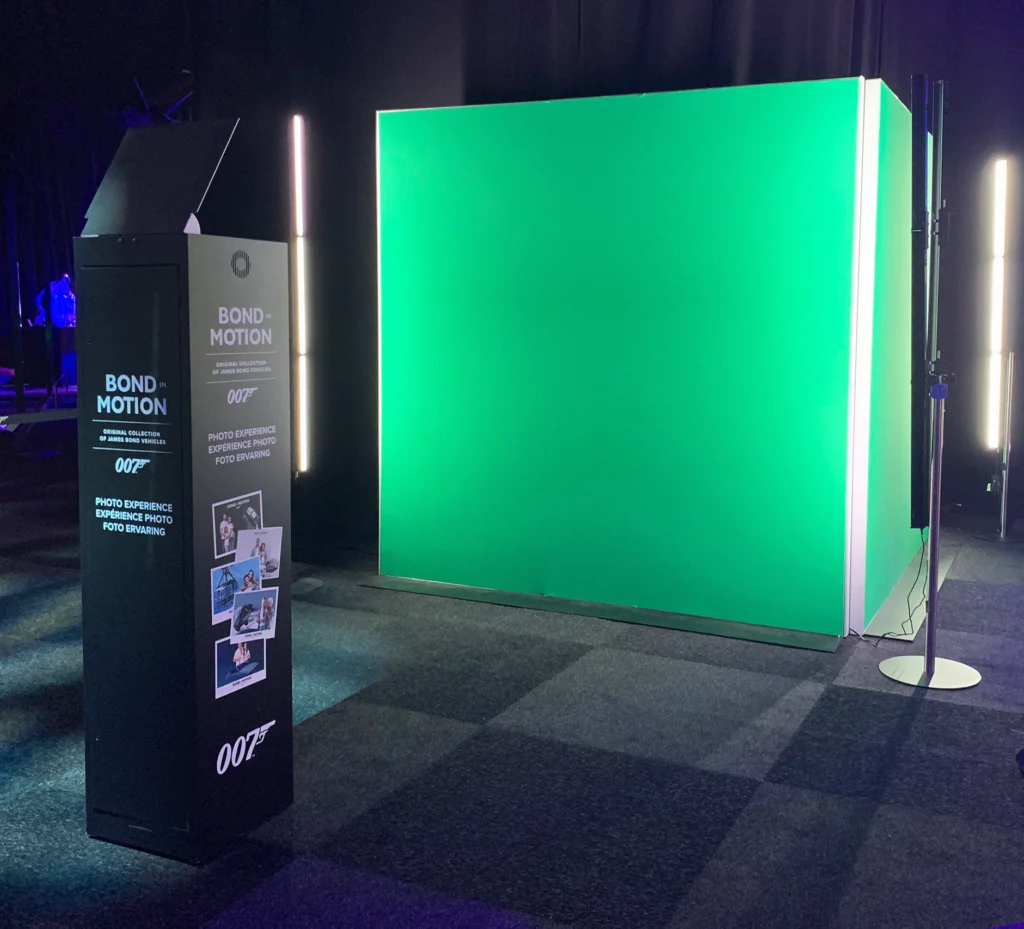 A green screen photo booth setup at the 'Bond in Motion' exhibition, providing an immersive photography experience for visitors.