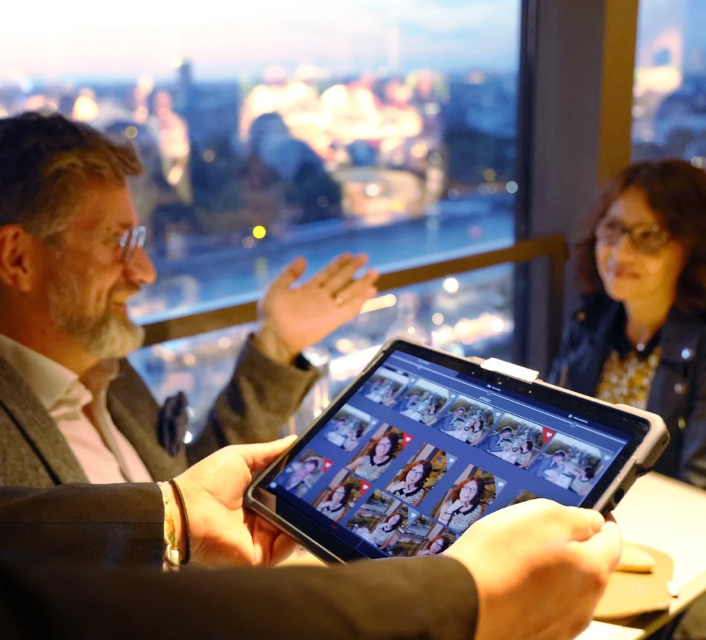 A patron at a dining event browses through a digital photo gallery on a tablet, showcasing memories captured by a professional photography service