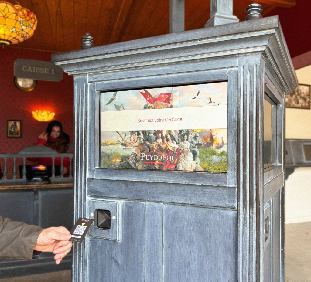 Guest scanning a QR code at Puy du Fou's interactive photo kiosk with vintage design elements